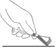 A hand holds a syringe and presses it against a flat surface to expel air