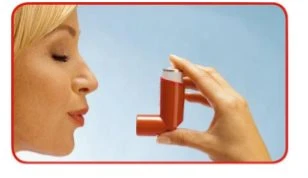 Profilo di una donna bionda che tiene un inalatore rosso con la mano destra vicino alla bocca per l