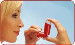 Profilo di una donna bionda che tiene un inalatore rosso aperto con entrambe le mani vicino alla bocca per l