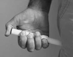 Una mano stringe saldamente un contenitore cilindrico bianco e sottile posizionato verticalmente contro il fianco di una persona