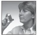 A woman with light hair holds an asthma inhaler near her face, looking toward the