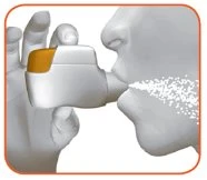 A hand holding a white and orange inhaler near a person's mouth, exhaling a cloud of nebulized spray