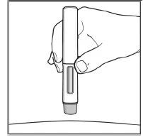 A hand holding a medical injection pen vertically, with a transparent indicator above a light curved surface
