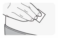 A hand holding a small rectangular plaster and placing it on the skin of the upper body or arm