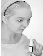 Close-up of a young woman with light hair tied back, intently looking at a small medicine bottle she is holding