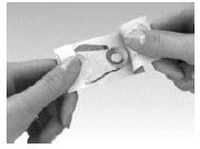 Due mani aprono con cura una piccola busta di carta o un involucro in materiale morbido per estrarre il contenuto medico