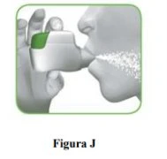 A hand holding a white and green inhaler near the mouth of a human profile emitting a cloud of nebulized spray