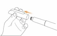 A hand holding a white cylindrical device while an orange arrow indicates the movement of inserting a component into the upper part