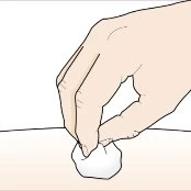 A hand gently pressing a white cotton ball onto a light skin surface