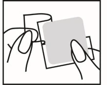 Two hands holding and peeling a gray adhesive cloth circle from a transparent square backing