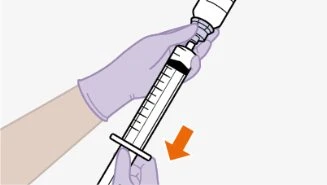 Una mano guantata tiene una siringa con un liquido scuro all'interno