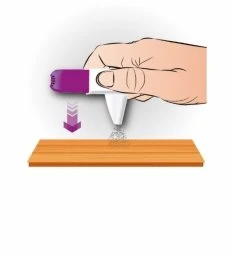 A hand pressing a white and purple medical device against a flat wooden surface with a purple arrow pointing downward
