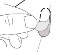 A hand gently lifting the edge of an oval-shaped grey tablet or coating against a white background