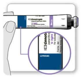 A hand holding a 12 mg Genotropin injection pen with a magnified view showing the field for expiration date and batch number