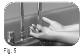 Two hands gripping and manipulating a medical device with vertical components and a metal base on a flat surface