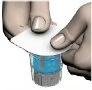 Two hands lifting a white adhesive disc above the cap of a medical vial containing blue liquid