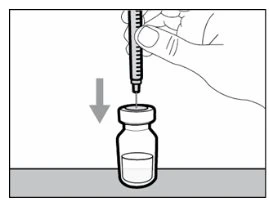 Una mano tiene una siringa con ago puntato verso il tappo di un flacone di medicinale con una freccia che indica il movimento verso il basso