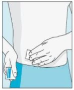 A hand holds a small white rectangular device while another hand prepares the injection site