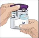 Две руки держат и нажимают на прозрачное медицинское устройство с фиолетовой крышкой для