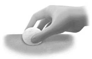 A hand pressing a white cotton pad onto the skin surface to apply medication or clean an area of the body