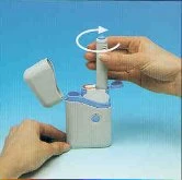 Due mani utilizzano un dispositivo medico bianco con coperchio aperto e una freccia bianca curva che indica il movimento di rotazione del cilindro