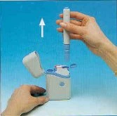 Una mano solleva un dispositivo medico cilindrico bianco da una base di plastica bianca su sfondo azzurro con una freccia bianca rivolta verso l'alto