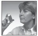 A woman with light hair and an earring holds a respiratory treatment inhaler between her fingers