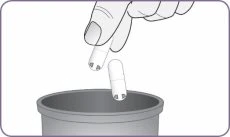 One hand holding a capsule above an open container while a