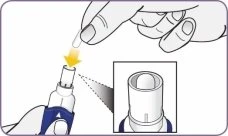 One hand inserting a white capsule into a cylindrical medical device, with an enlarged detail showing the capsule entering the