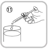 Una mano impugna una siringa inclinata per far cadere delle gocce di liquido all'estremità