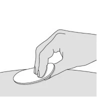A hand holding and pressing a flat white circle onto a light skin surface for application