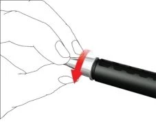 Una mano tiene un dispositivo medico cilindrico nero e argento con una freccia rossa che indica il movimento di rotazione verso il basso