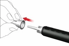 Una mano impugna un tappo cilindrico che viene avvicinato e inserito sulla parte superiore di un dispositivo medico nero con punta metallica