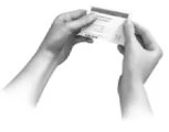 Two hands holding and displaying a small rectangular instruction leaflet with text and symbols on a white background