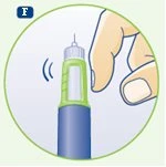 A hand holding a blue and green cylindrical medical device with an exposed needle at the top on a white background surrounded by a green border