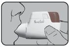 Profile of a face inhaling medication from a white medical device held by one hand between mouth and nose