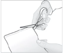Una mano tiene un paio di forbici aperte per tagliare il bordo superiore di un sacchetto o di un involucro tenuto dall'altra mano