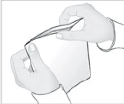 Due mani che tengono e separano con cura una bustina o un involucro di carta bianco per estrarne il contenuto