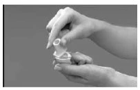 Two hands hold and manipulate a white medical device consisting of a cylindrical container and a flat base on a gray background