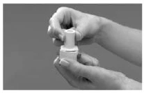 Two hands hold and manipulate a white cylindrical medical device composed of two interlocking parts on a gray background