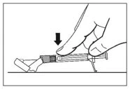 A hand pressing down with the thumb on a syringe plunger