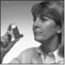 A woman with short hair carefully holds and examines an inhaler for respiratory treatment in a black-and-white photo