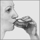 A person's profile drinking from a cup held in the right hand to take a liquid medication