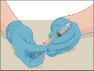 Two hands with blue gloves holding a syringe with needle and a medication vial to prepare the injection