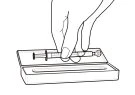 Disegno a linee nere di una mano che tiene una siringa orizzontalmente sopra una scatola rettangolare aperta con un contenitore interno