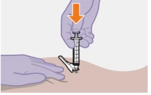 A gloved hand pressing down a syringe with a needle penetrating the skin of the thigh while another...