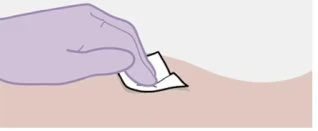 A gloved hand pressing a small white adhesive bandage onto a light skin surface to apply it correctly