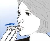 Disegno di una donna di profilo che inserisce una compressa in bocca con la mano, indicata da una freccia blu verso la bocca aperta