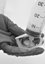 A gloved hand holding a glass vial while a