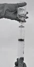 A gloved hand holding a glass ampoule while a